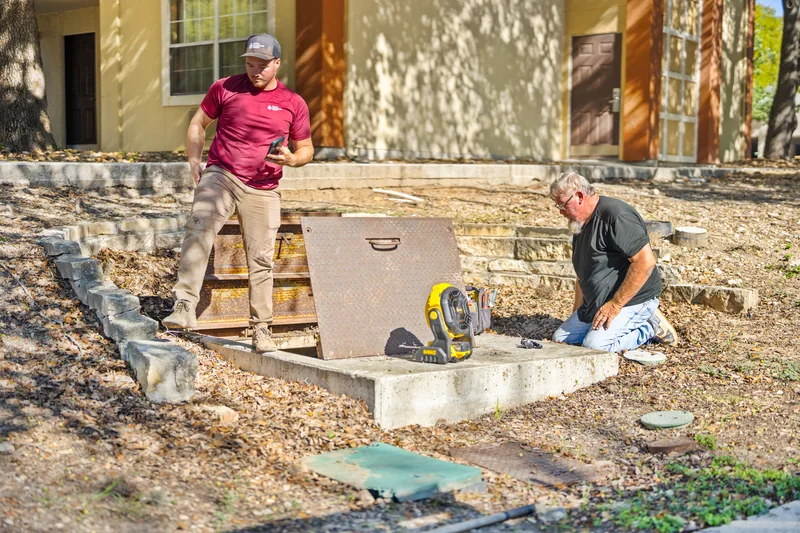 Two H2O Plumbing Authority team members beside an open valve vault at a commercial job